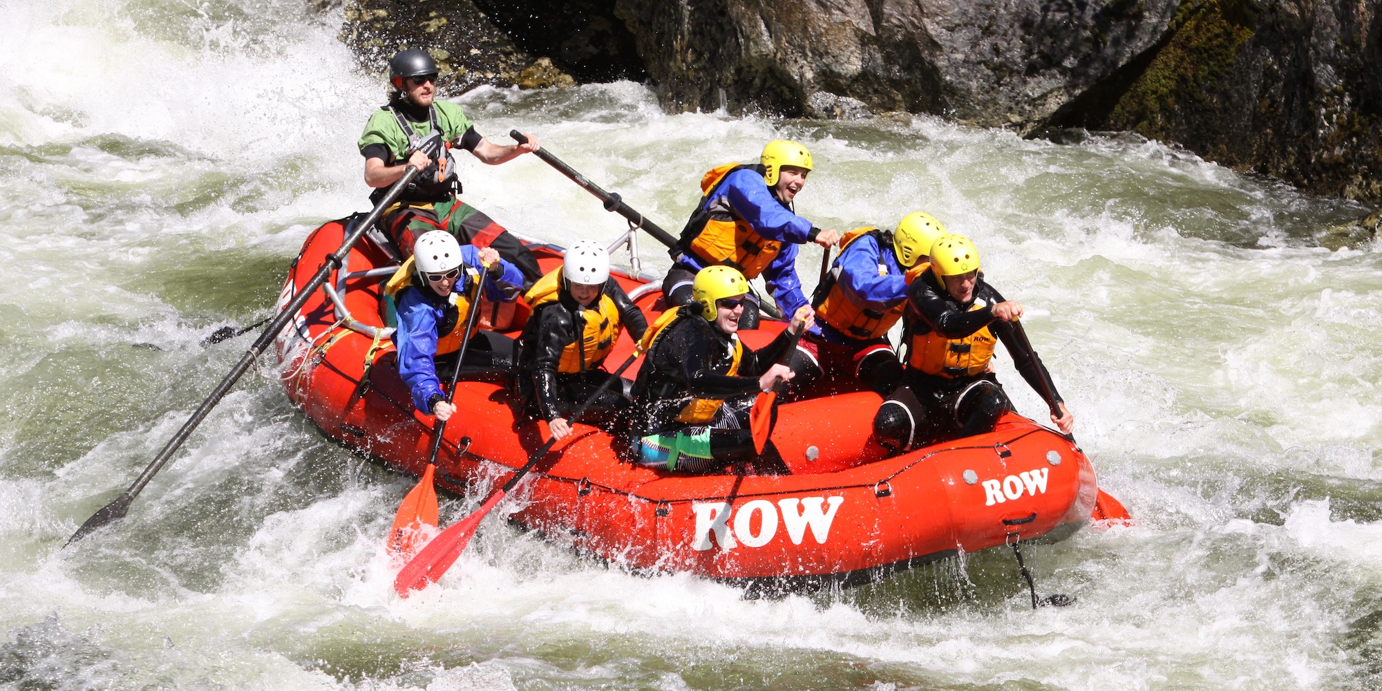 A raft filled with paddling customers navigating down a large rapid on the Lochsa river.
